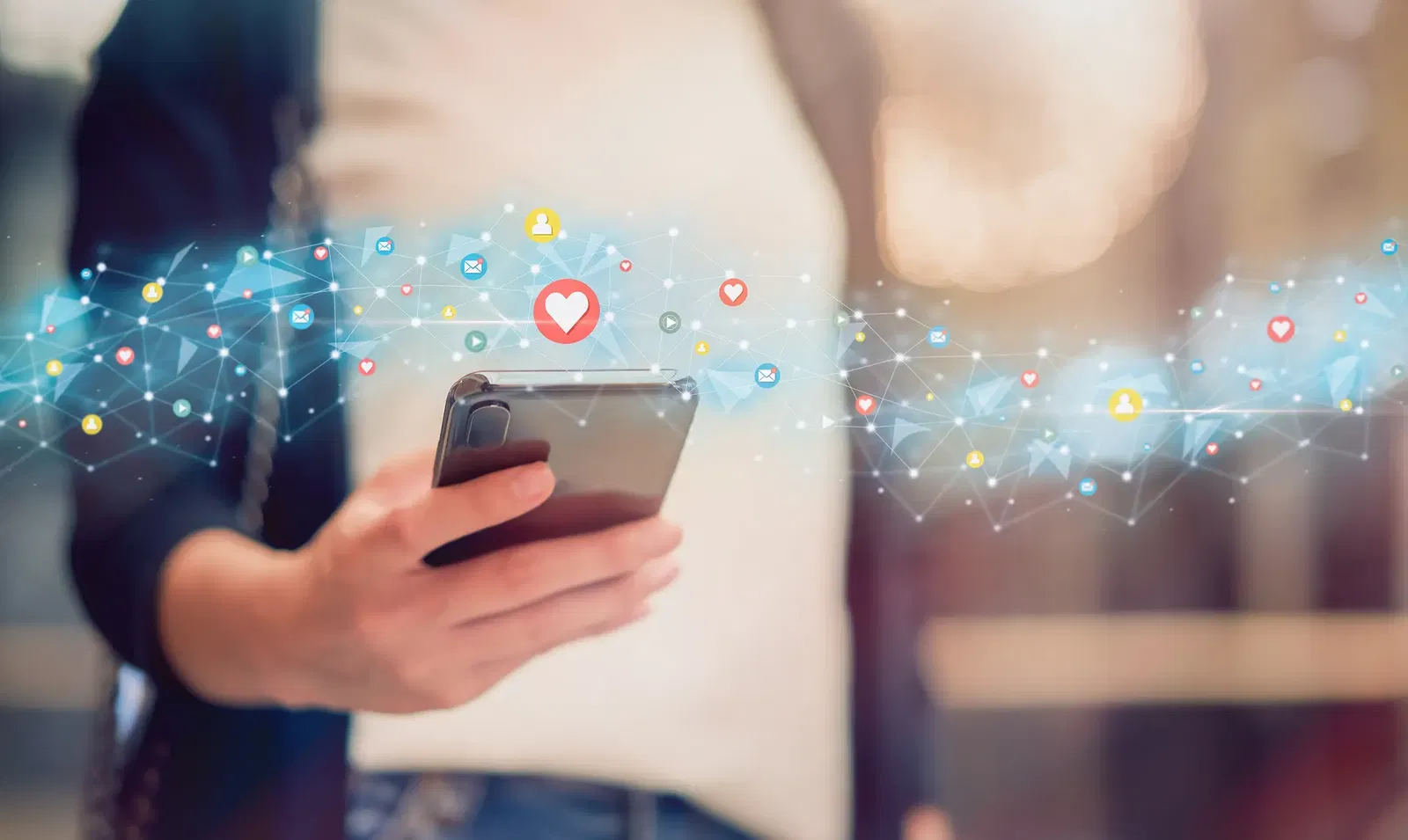 Social Media Marketing Person hält Smartphone, darüber fliegen Social-Media-Symbole wie Herz, Like, Nachricht und Netzwerk – Symbol für digitale Interaktion und Online-Kommunikation.