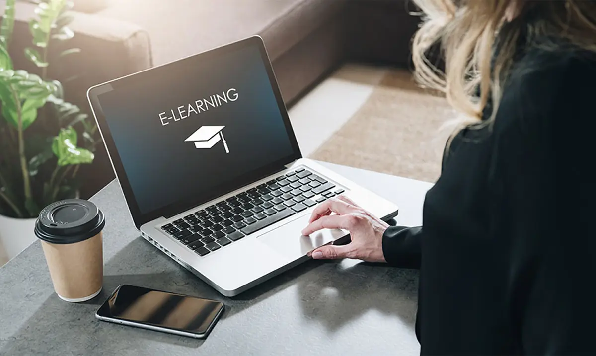 Training Frau vor Laptop mit E-Learning-Symbol auf Bildschirm im Format 920x550