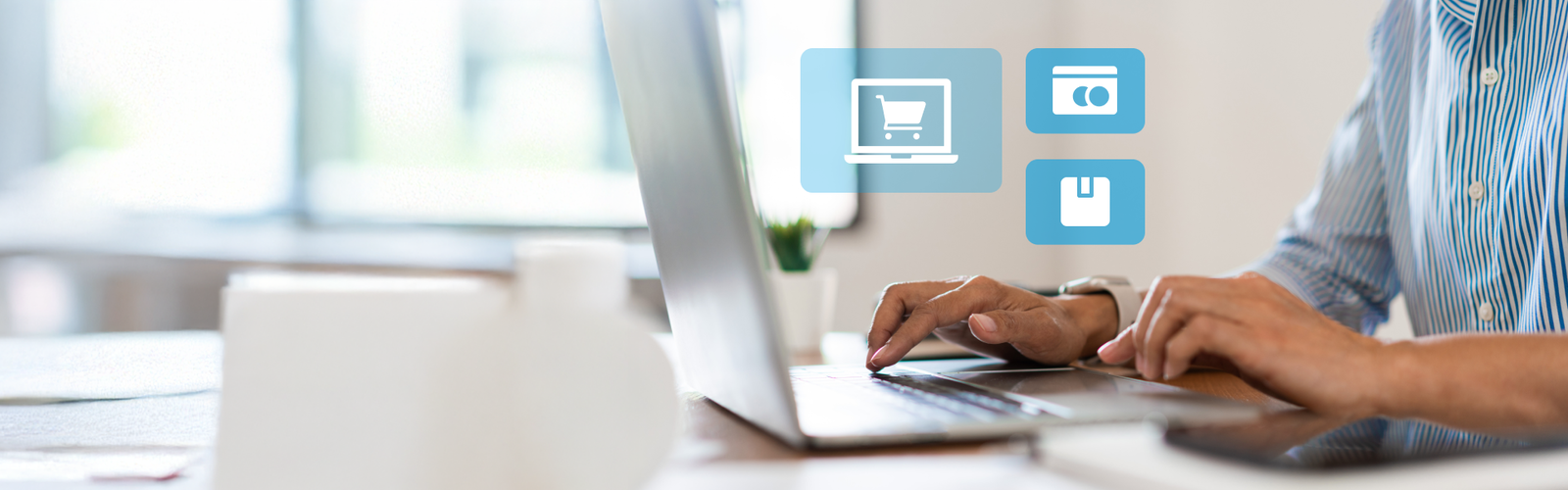 Person sitzt vor einem Laptop mit schwebenden Symbolen über der Tastatur, symbolisch für E-Commerce