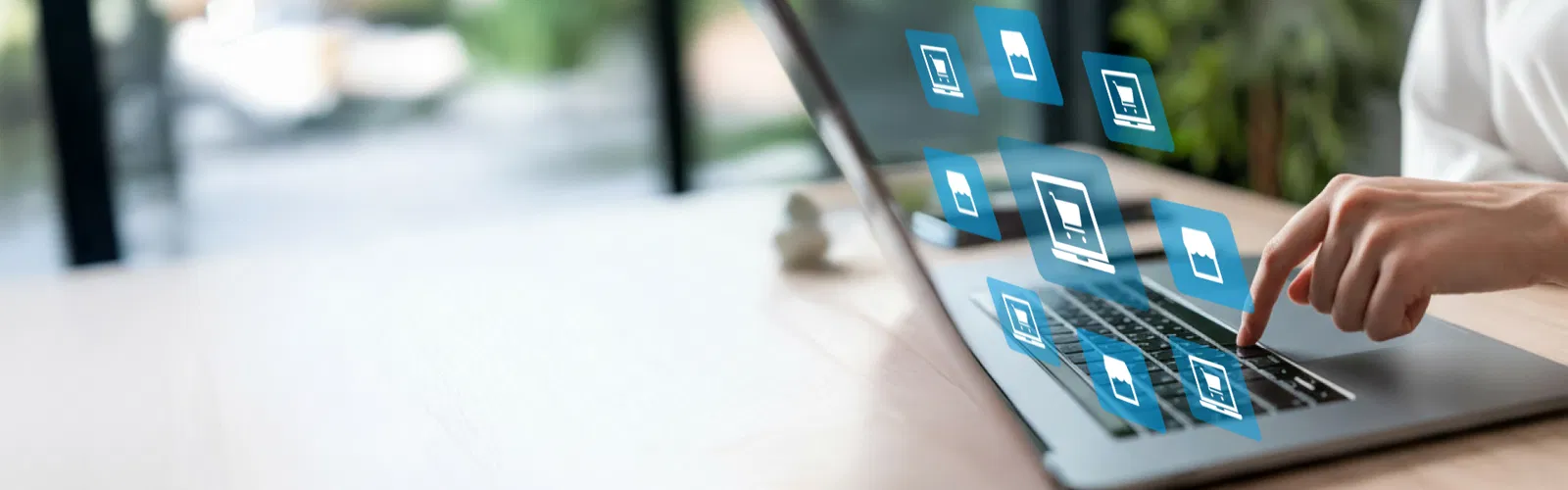 Person tippt auf Laptop-Tastatur, umgeben von schwebenden blauen Symbolen für digitale Anwendungen – Symbol für Digitalisierung und vernetzte Systeme.