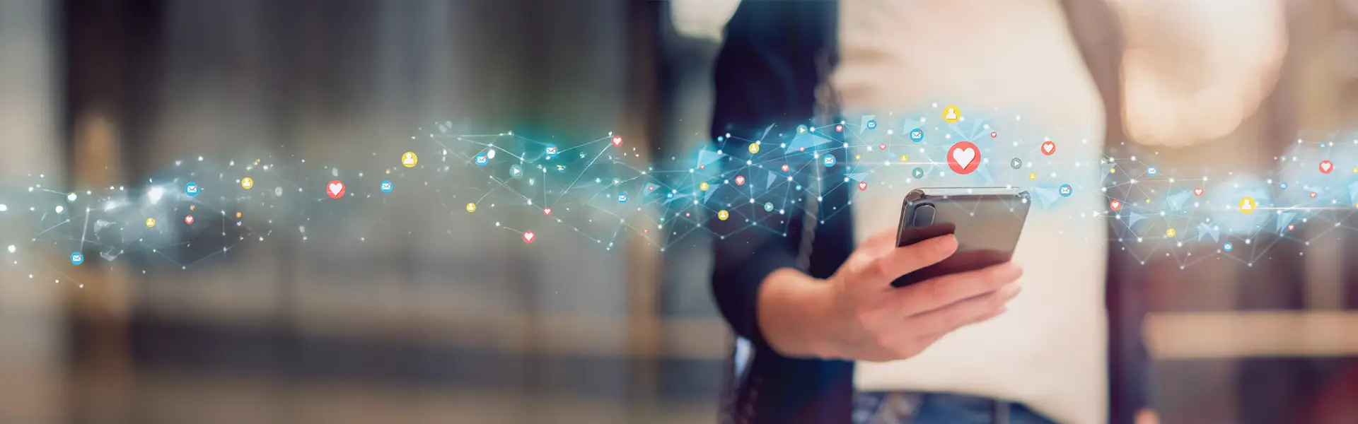 Social Media Agentur Person hält ein Smartphone, über dem digitale Symbole für soziale Medien und Netzwerke schweben – symbolisiert digitale Kommunikation und Social Media Interaktion.