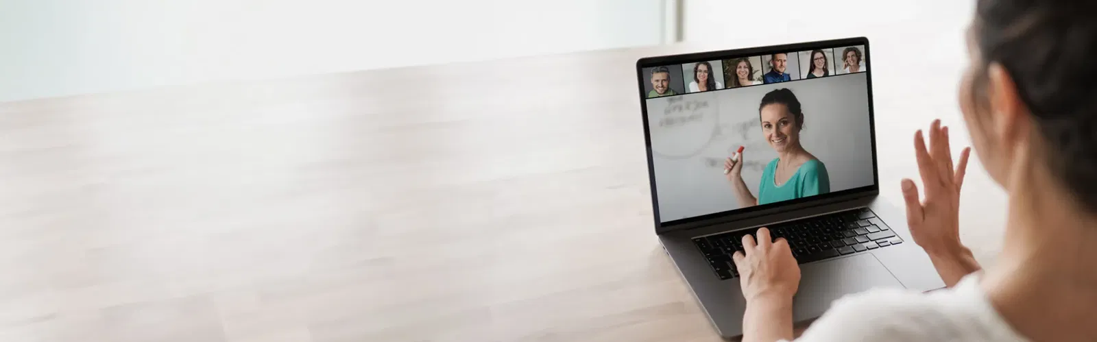 IT-Schulungen und Weiterbildungen Frau nimmt an einer Videokonferenz über ihren Laptop teil und kommuniziert mit anderen Teilnehmern.