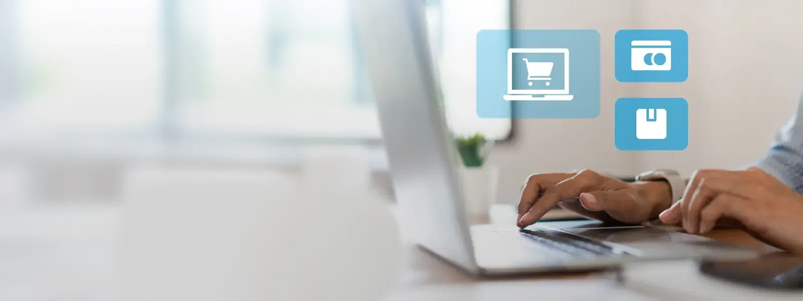 Person sitzt vor einem Laptop mit schwebenden Symbolen über der Tastatur, symbolisch für E-Commerce
